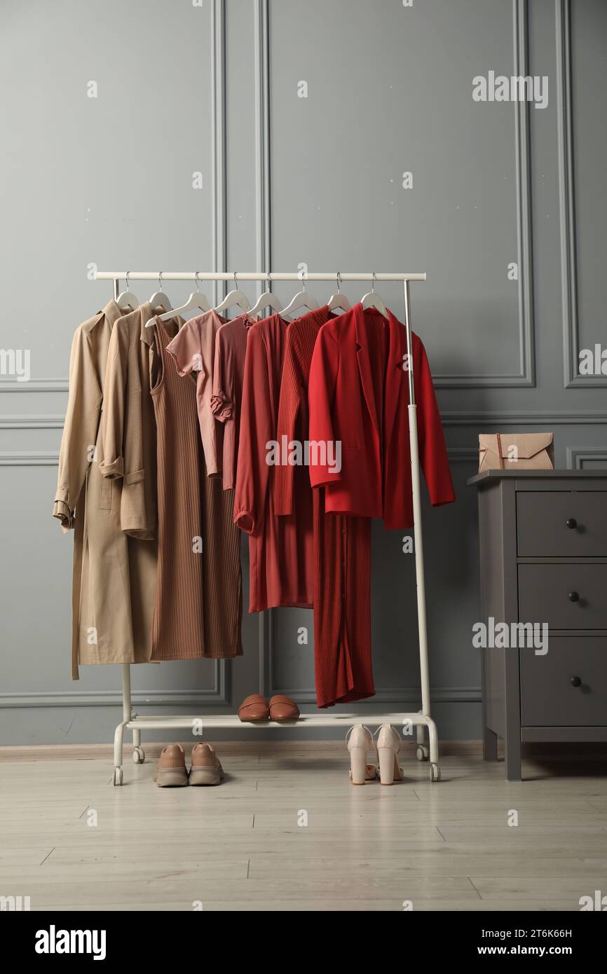 Rack with different stylish women`s clothes, shoes and bag on chest of